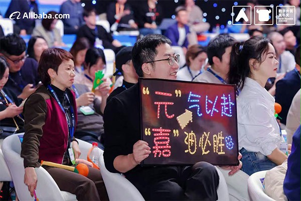 上图为：后援团举出“元气以赴，嘉油必胜”的牌子为杨元嘉加油鼓劲